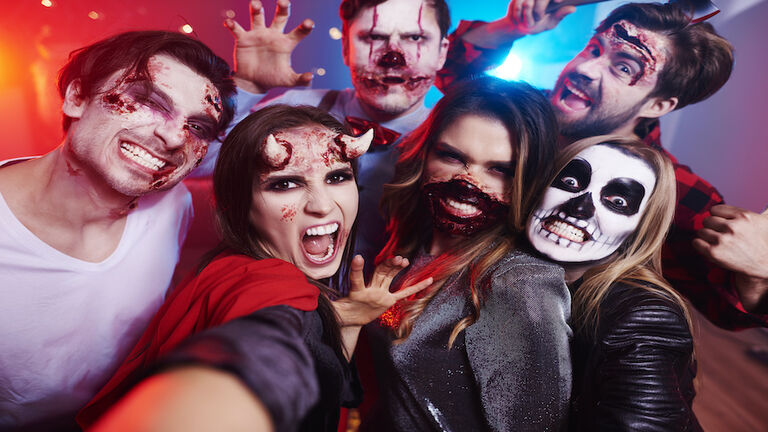 Friends in creepy costumes having fun at Halloween party