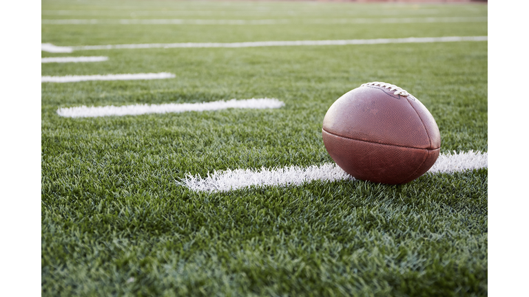 Close up of American football ball on green playing field