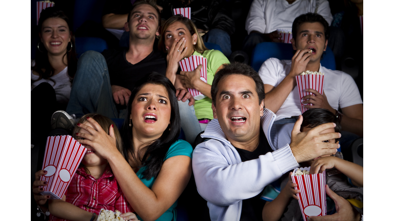 Frightened Hispanic family watching film in movie theater