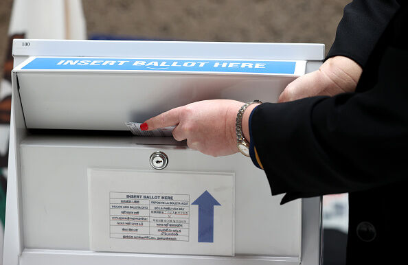  County election official inserting a ballot into a ballot collection box during a recent demonstration.