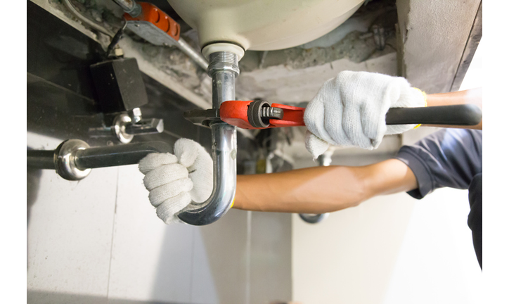 Cropped Hands Of Plumber Repairing Pipe