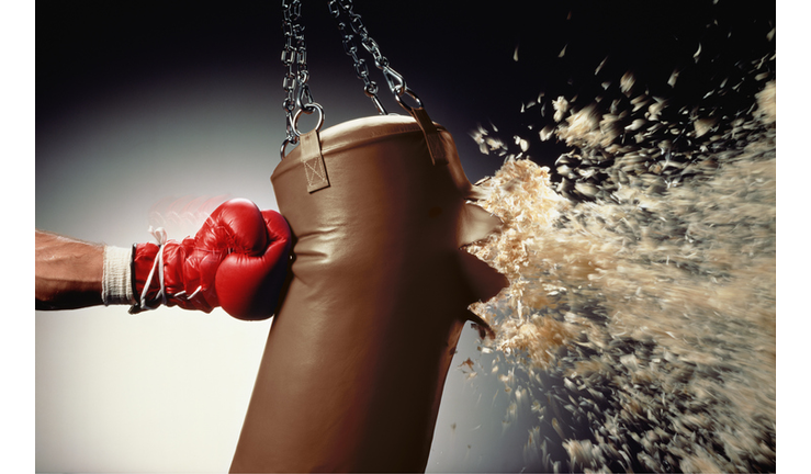 Man punching punch bag and stuffing exploding from bag