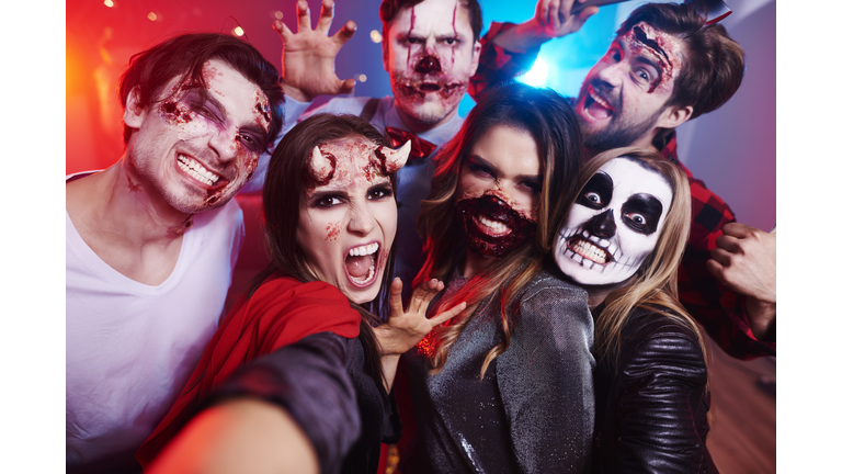 Friends in creepy costumes having fun at Halloween party