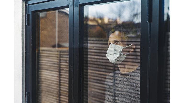 Man with mask looking out of window