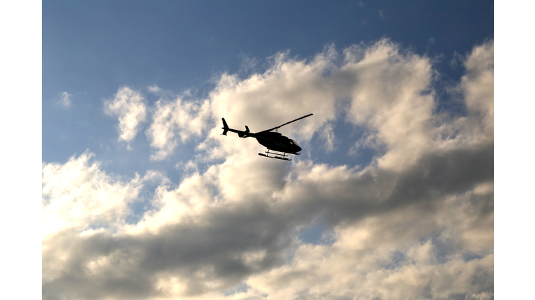 Silhouette of a Helicopter flying in the partially cloudy sky