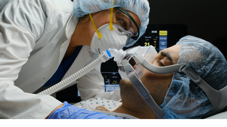 Female doctor checking on Covid-19 infected patient while connected to a ventilator