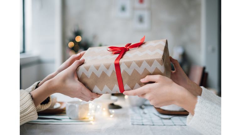 Woman giving her friend a wrapped Christmas gift