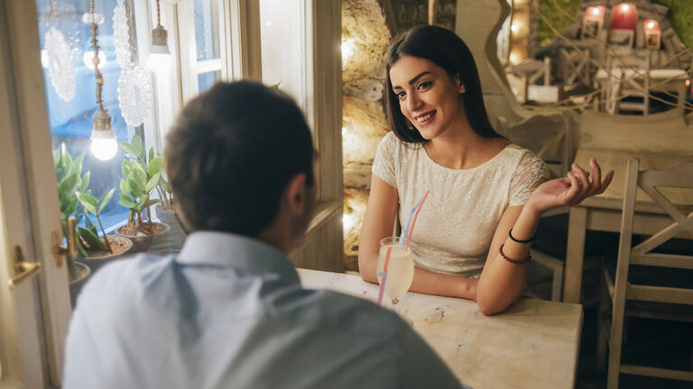 Portrait of smiling young woman talking to her boyfriend in a restaurant