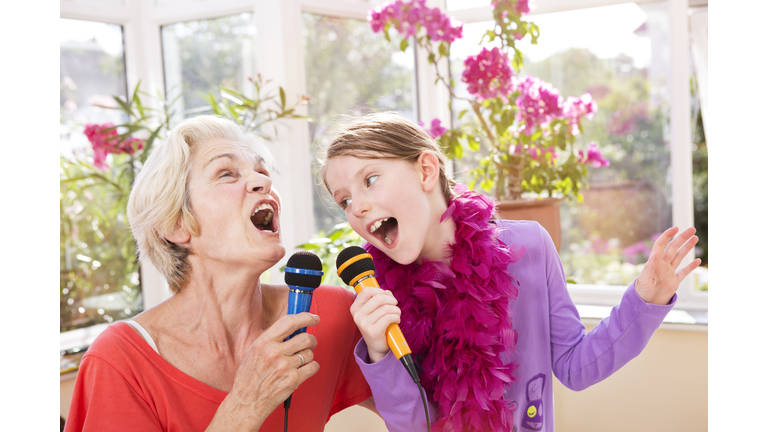 Grandmother and grandchild singing karaoke.