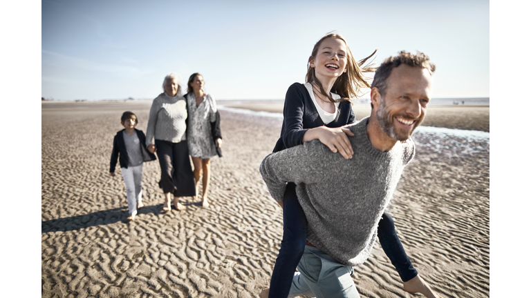 Happy father carrying daughter piggyback on the beach