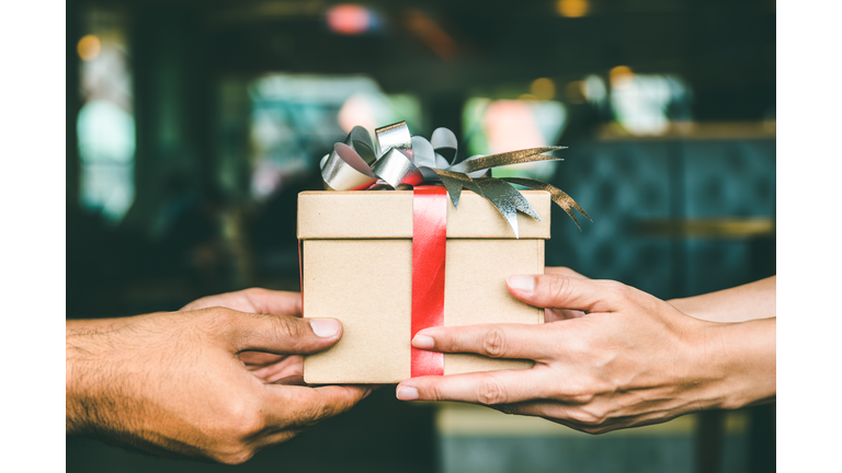 Cropped Hand Of Man Giving Christmas Present To Female Friend