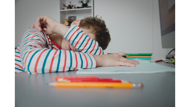 Child tired and bored of doing homework, kid stressed from learning indoors