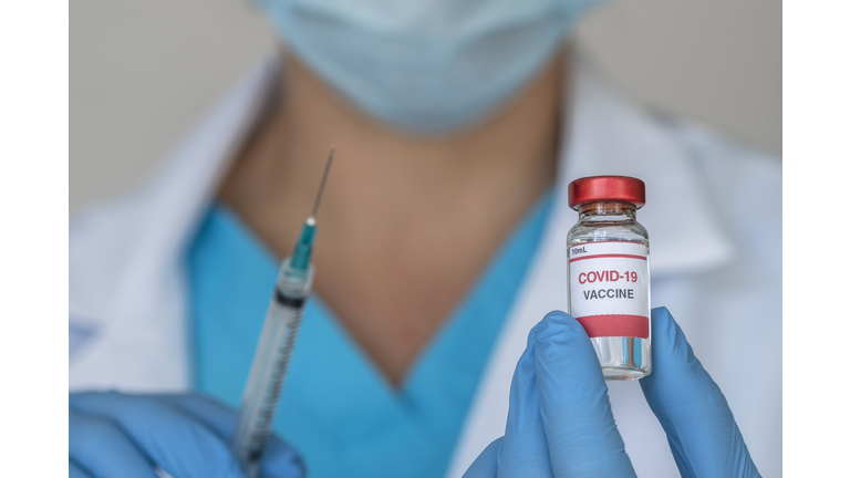 Close-up of doctors hands holding Covid-19 vaccine and syringe