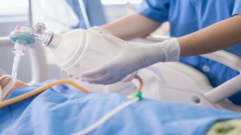 Doctor holding oxygen ambu bag over patient given oxygen to patient by intubation tube in ICU/Emergency room