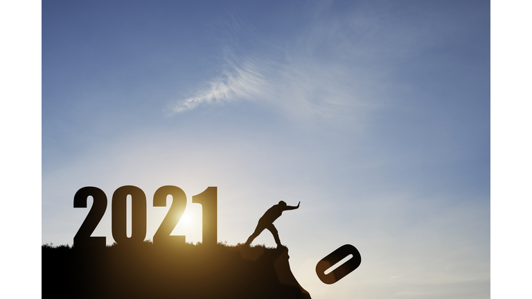 Man push number zero down the cliff where has the number 2021 with blue sky and sunrise. It is symbol of starting and welcome happy new year 2021.