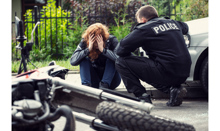 Terrified victim of a traffic collision of motorcycle with a car and policeman