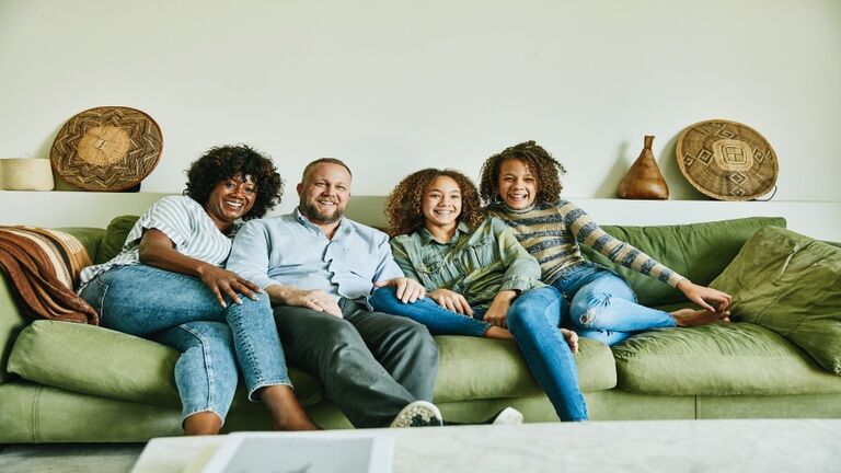 Portrait of smiling family sitting on couch in living room