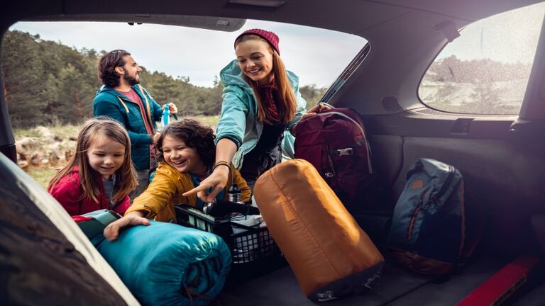 Young family getting the camping supplies out of the car