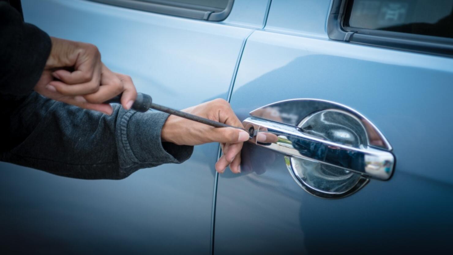 A young man who is breaking into a car