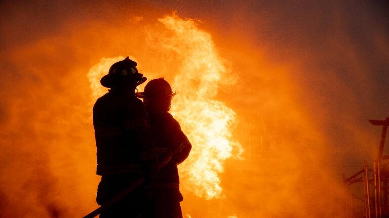 Silhouette of two firefighter in front of the big fire, Fire insurance concept