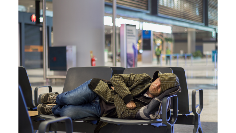 Young man sleeping while waiting the plane at airport passenger terminal