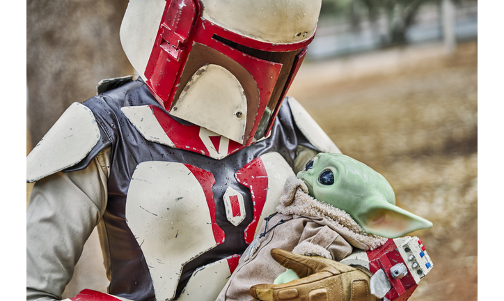 Cartagena, Murcia, Spain - December 28, 2020: Girl in a Mandalorian costume holding Baby Joda (Grogu) in a park as if it were a baby