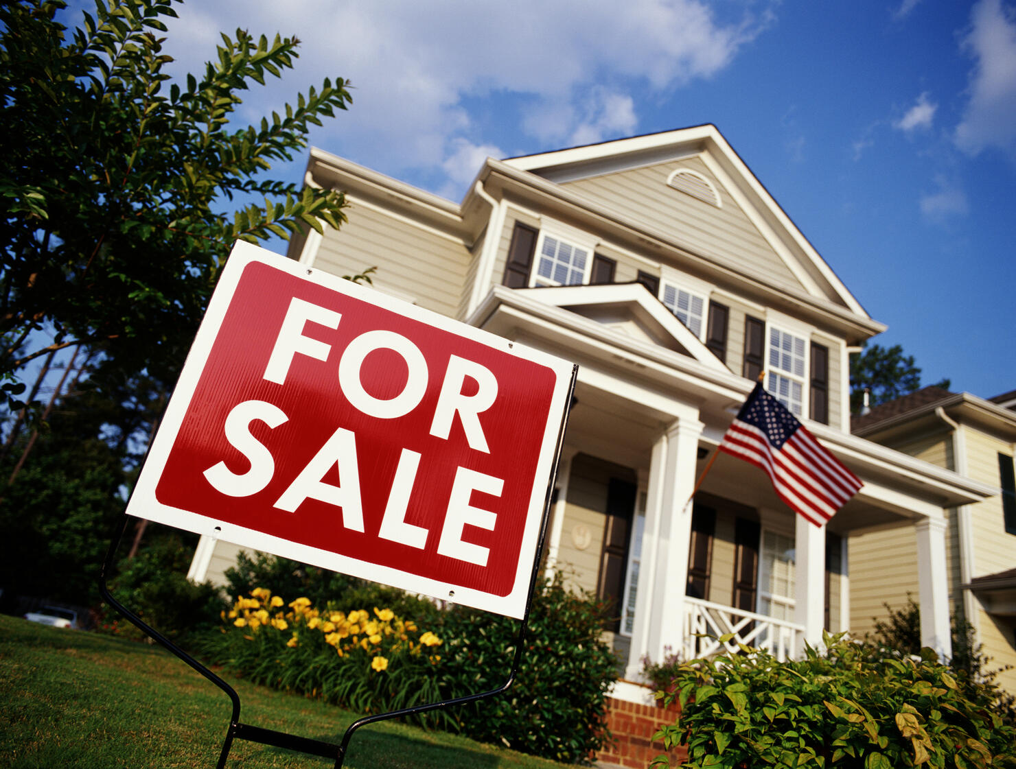 House with American flag and 'for sale' sign, low angle view