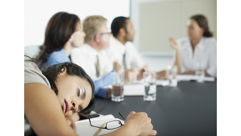 Businesswoman sleeping in conference room during meeting