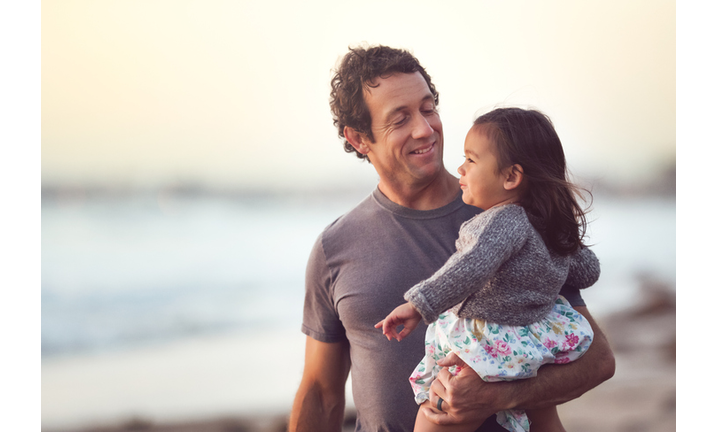 Smiling Dad Holds His Toddler Daughter Outdoors