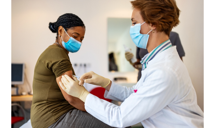 General practitioner giving flu shot to a senior woman