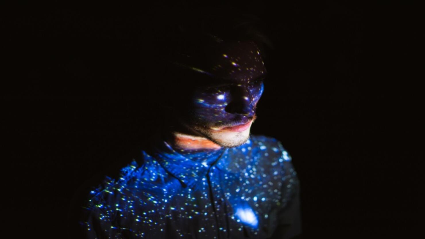 Man covered by colorful abstract patterns projected onto his face