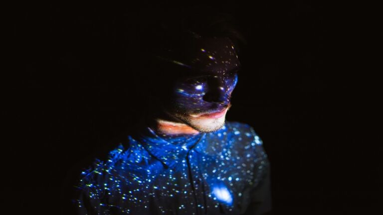 Man covered by colorful abstract patterns projected onto his face