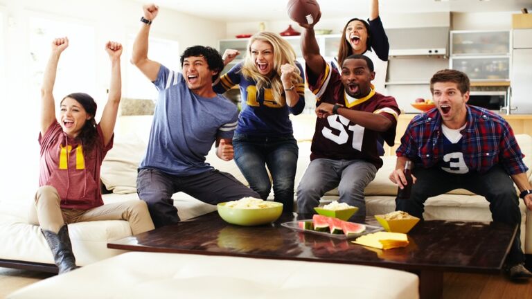 Friends watching football in living room.