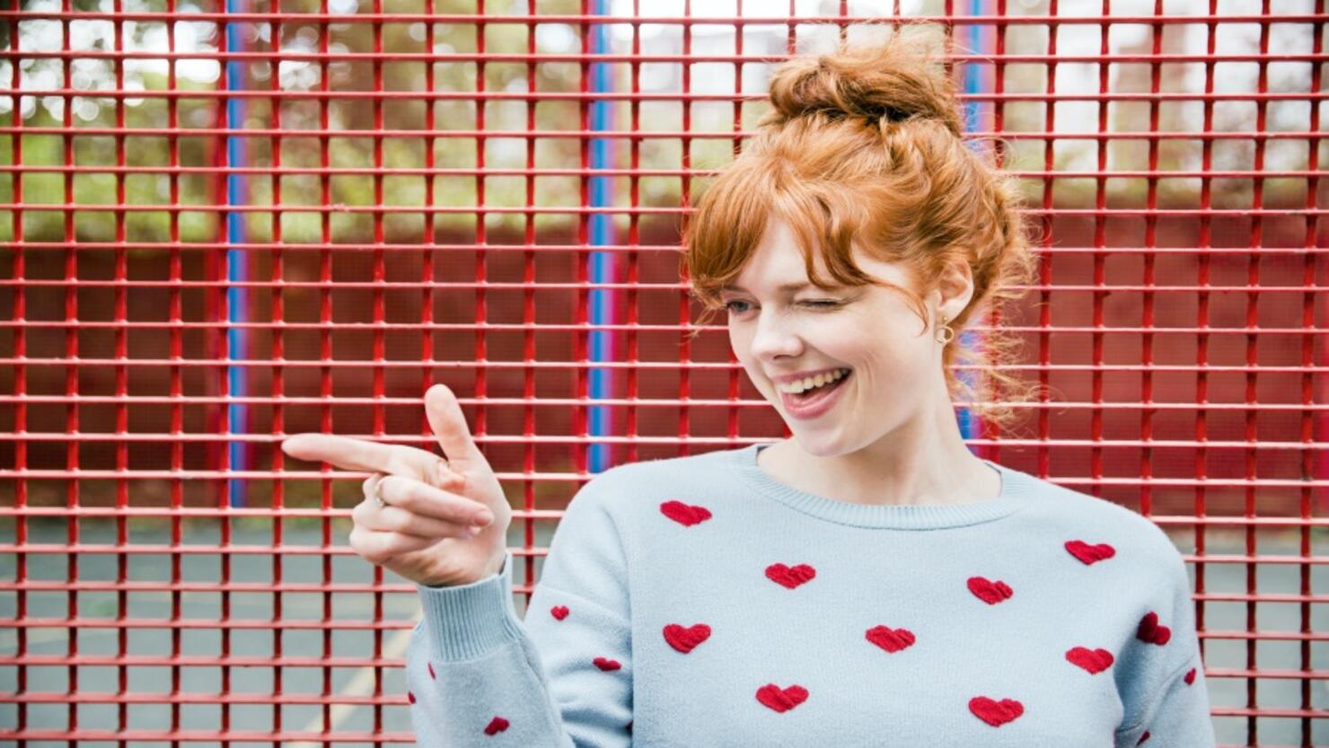 Young woman winking and pointing.