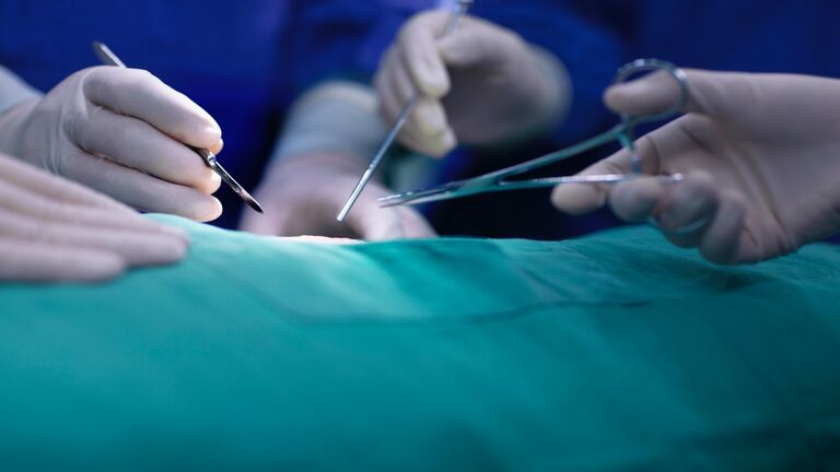 Hands of operating room staff performing surgery