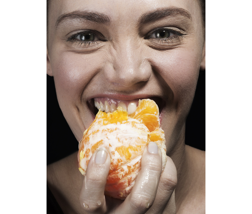 Female biting an orange