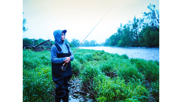 Boy fly-fishing on a trout stream