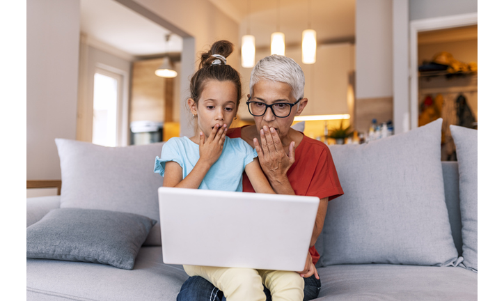 Grandmother and child looking at laptop with suprise