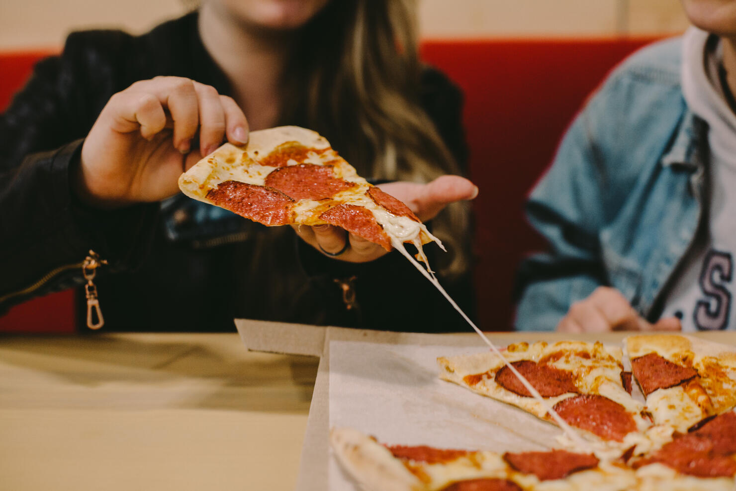 Cropped image of woman holding pizza slice at restaurant