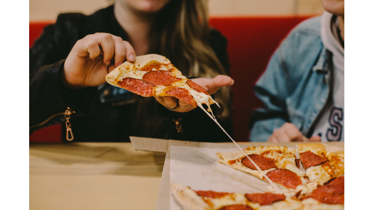 Cropped image of woman holding pizza slice at restaurant