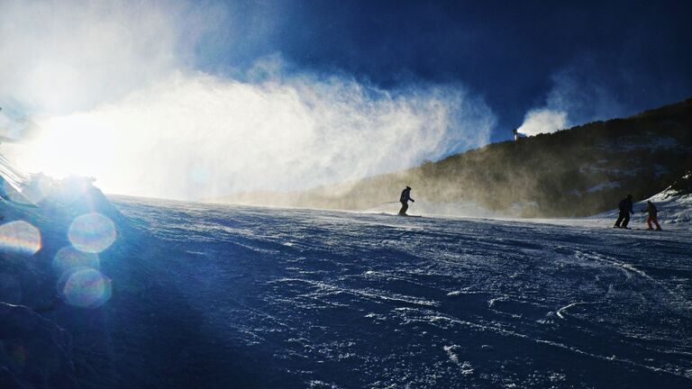 Snowmaking On Slope. Skier Near A Snow Cannon Making Fresch Powder Snow. Ski Resort And Winter