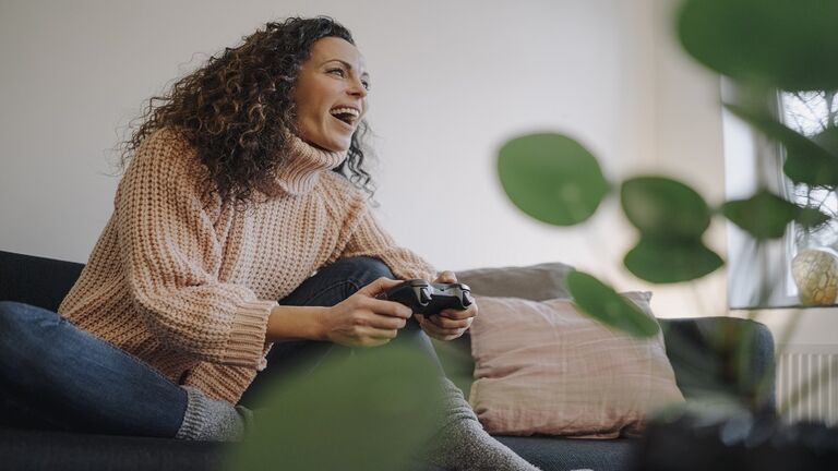 Woman sitting on couch, having fun, playing with a gaming console