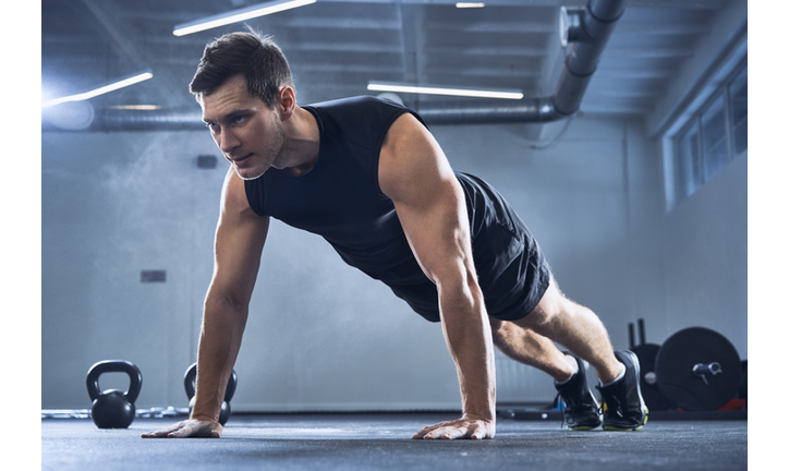 Athletic man doing pushups exercise at gym