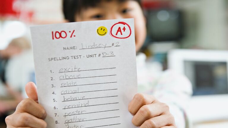 Elementary student holding an A grade paper