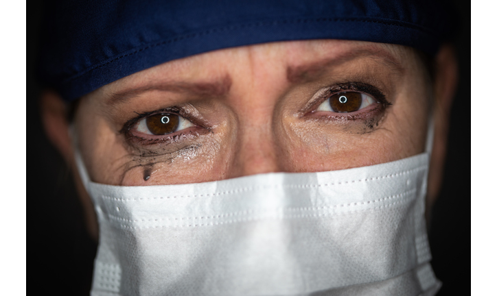 Tearful Stressed Female Doctor or Nurse Wearing Medical Face Mask on Dark Background