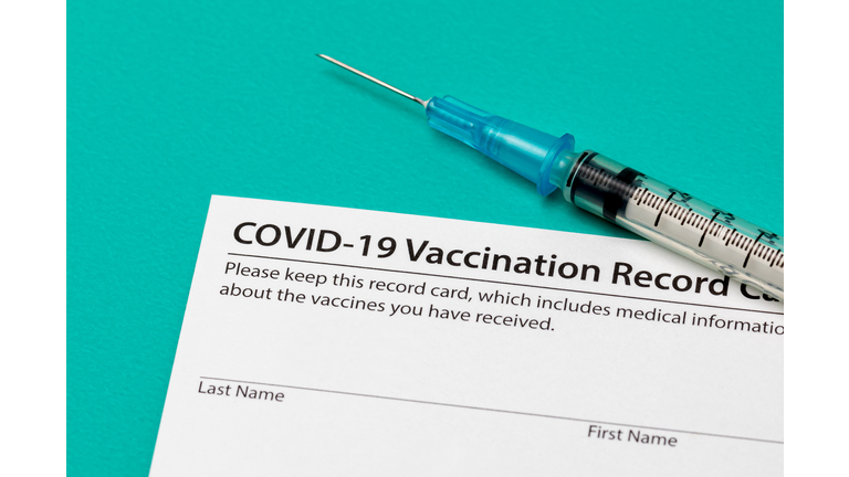 Covid-19 coronavirus vaccination record card with syringe and needle. Concept of vaccination, herd immunity and pandemic healthcare.