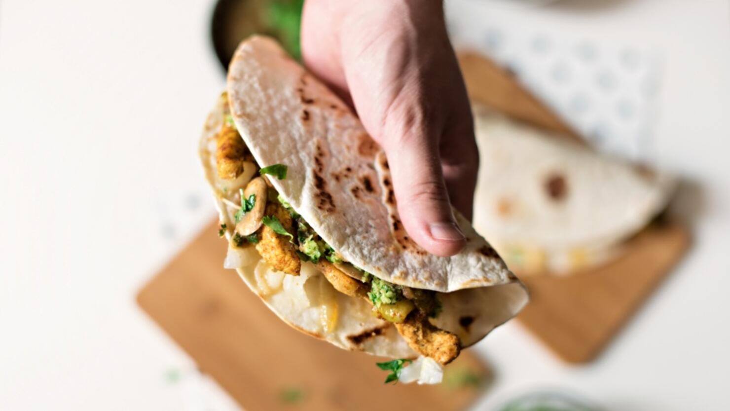 Human hand holding homemade chicken taco