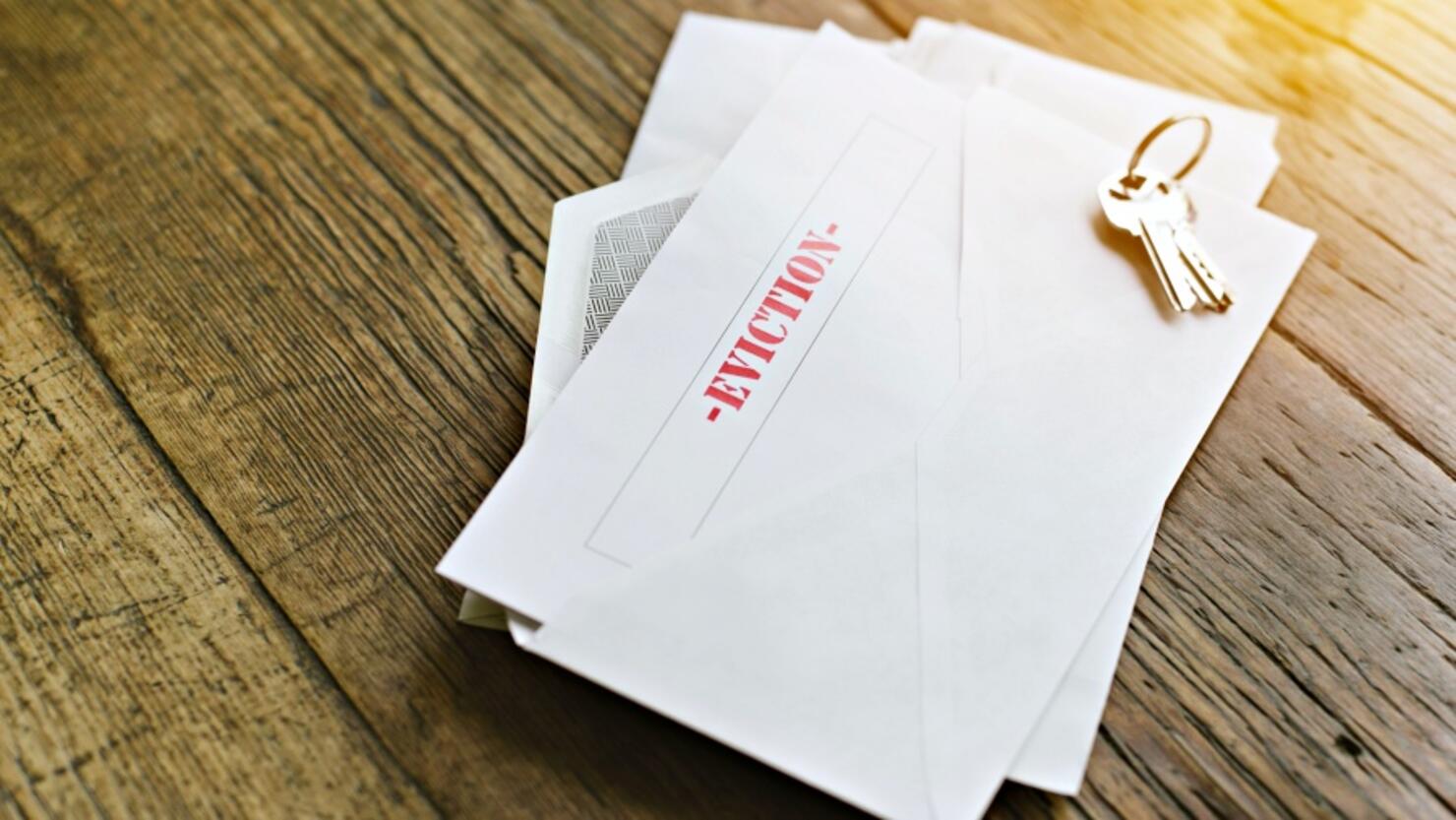 Notice of Eviction Opened in an Envelope with House Keys on a Wood Table - Sun shining through - Late Rent - Mortgage