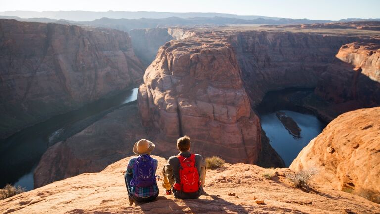 A couple hiking on the edge of a senic overlook.