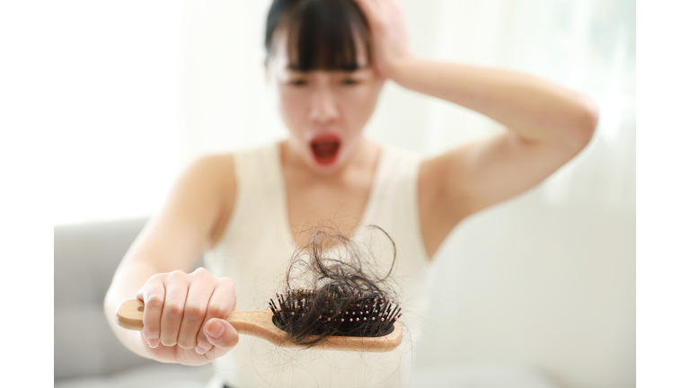 Worried woman holding hairbrush with loss hair